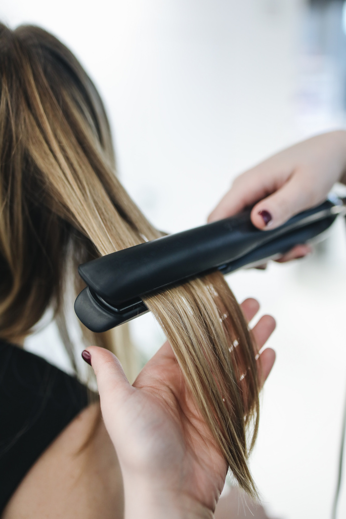 Person Ironing a Woman's Hair